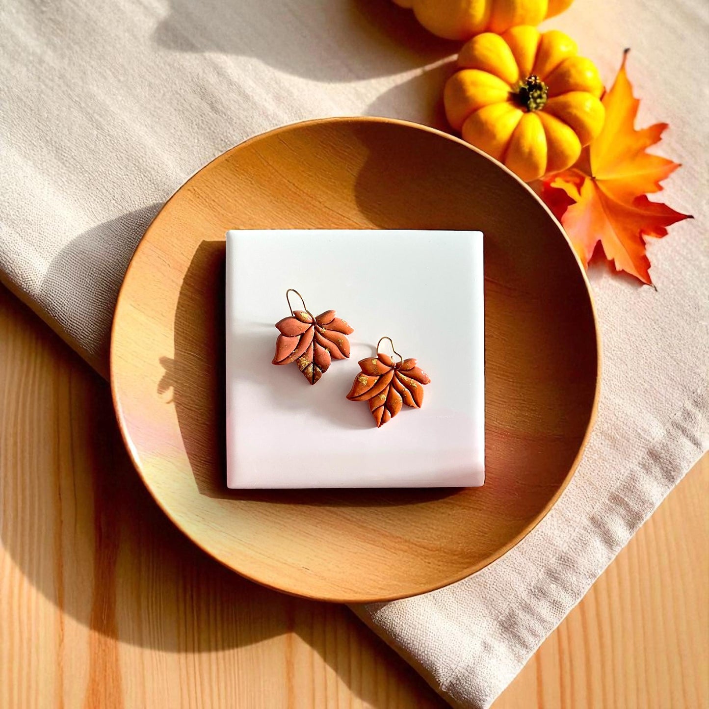 Small leaf clay cutter displayed on white tile with pumpkins and yellow leaves