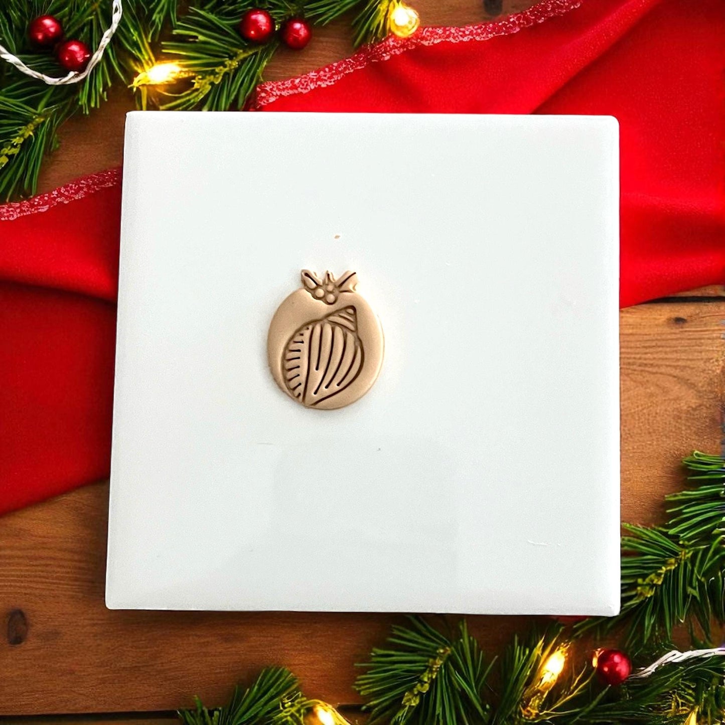 Shell clay cutter and clay impression displayed side by side with festive holiday lights