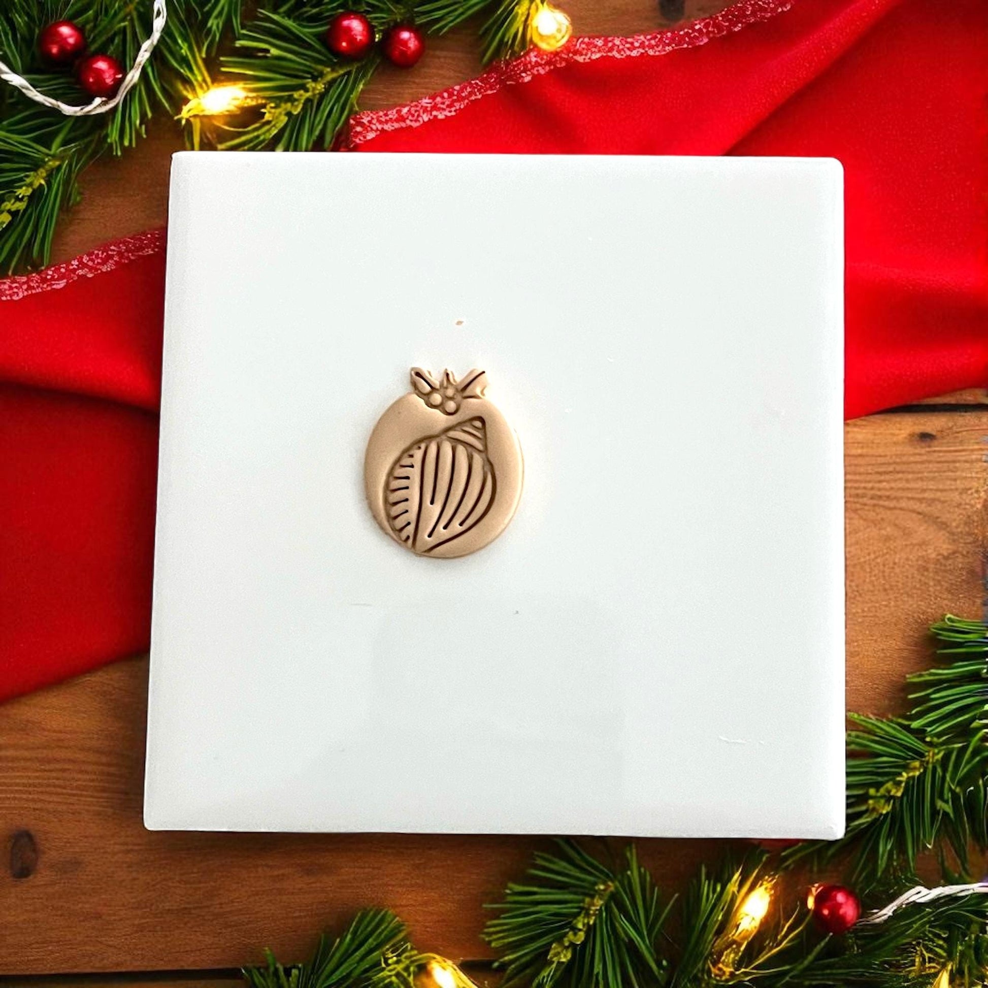 Shell clay cutter and clay impression displayed side by side with festive holiday lights