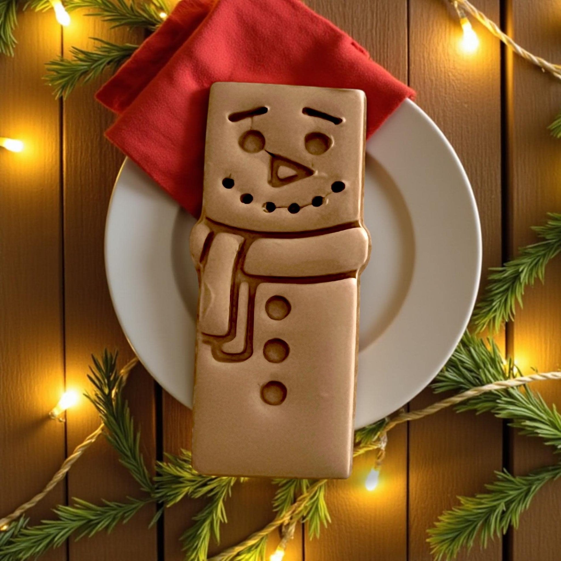 Snowman bar clay impression displayed on white tile with red fabric and pine