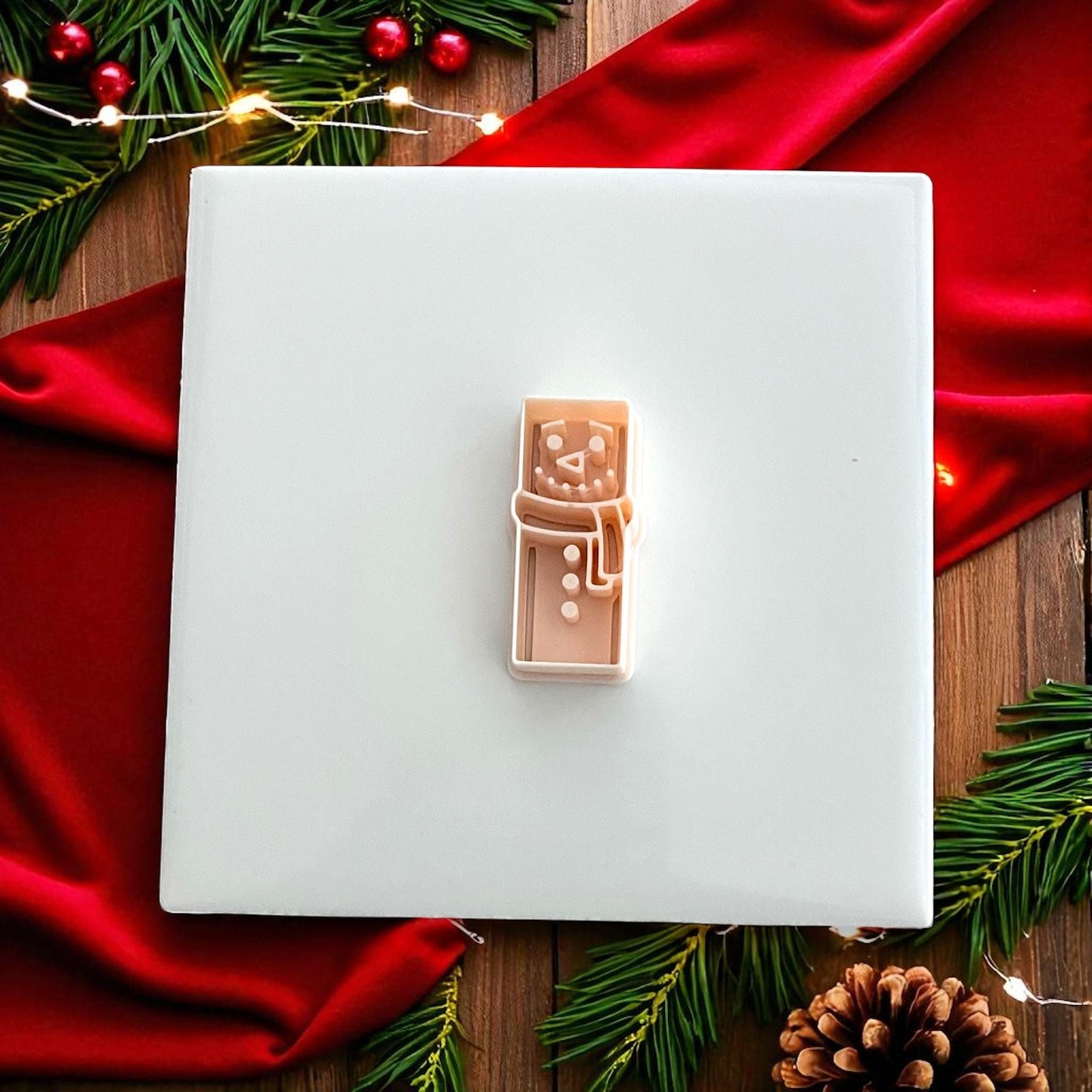 Snowman polymer clay cutter on white tile with Christmas lights and decor