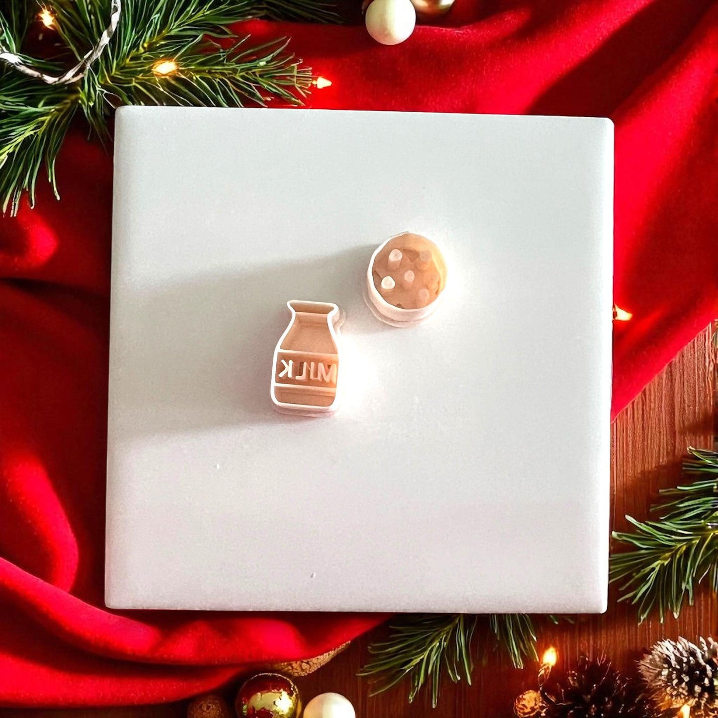 Christmas earring made from milk and cookie cutters displayed under tree with lights