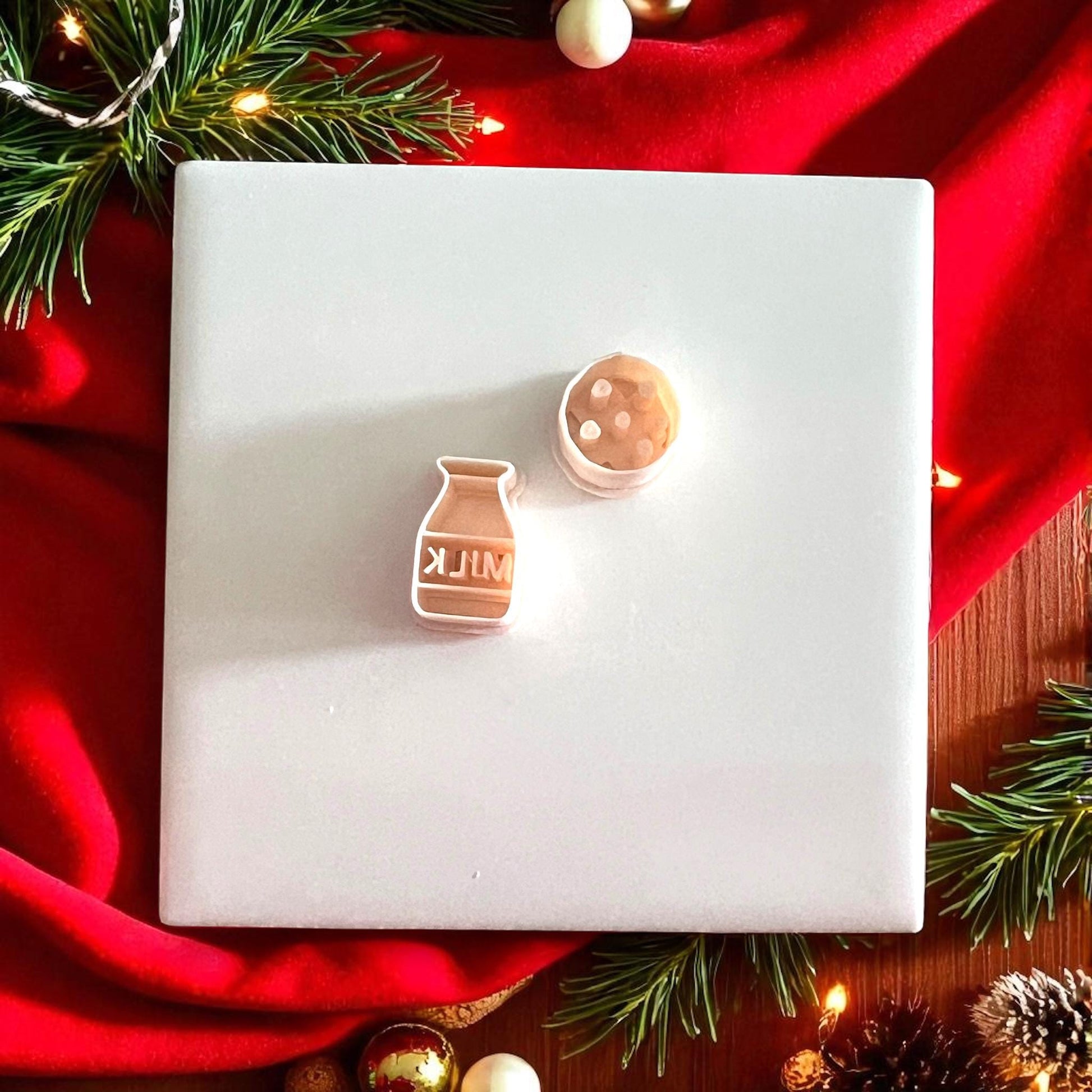 Christmas earring made from milk and cookie cutters displayed under tree with lights