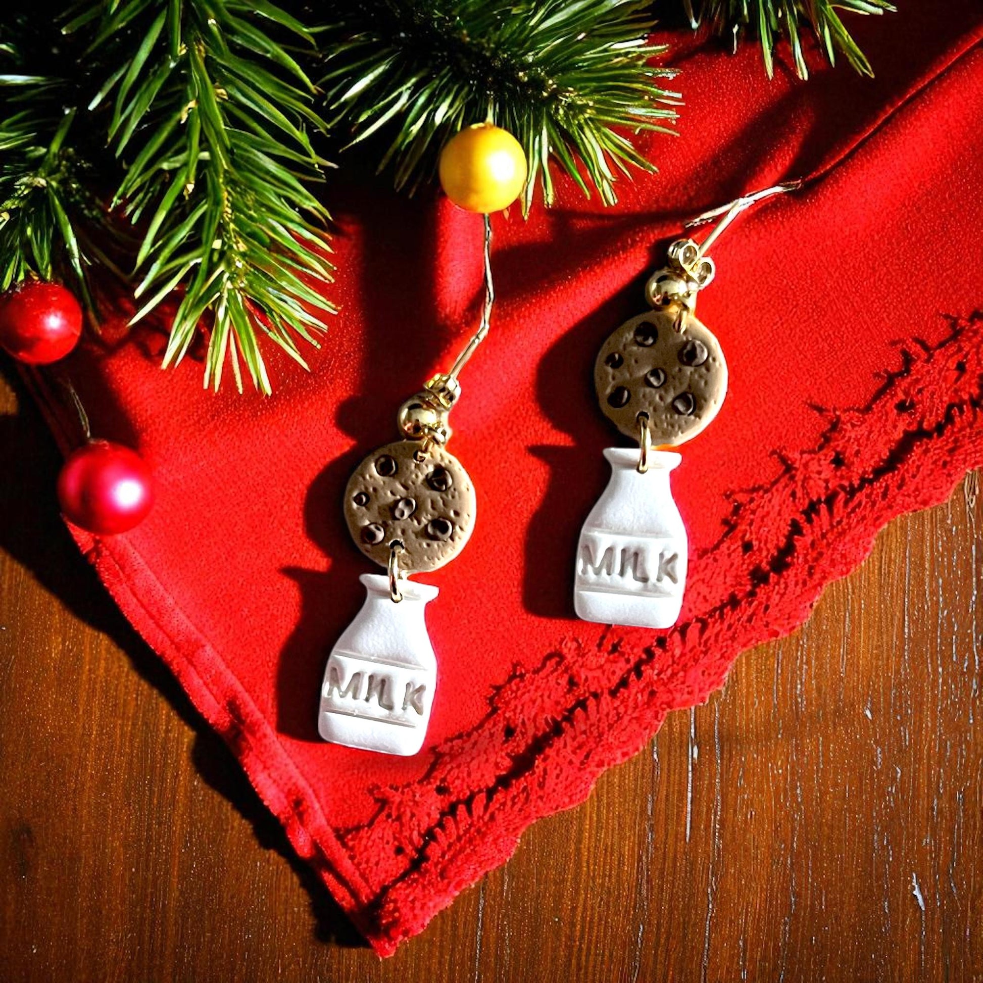Polymer clay milk and cookie earrings on red fabric with Christmas decorations