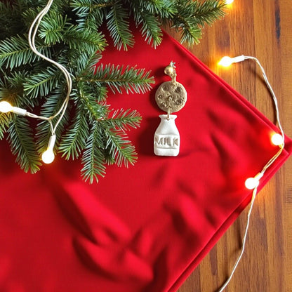 Polymer clay milk and cookie earrings on red fabric with Christmas decorations