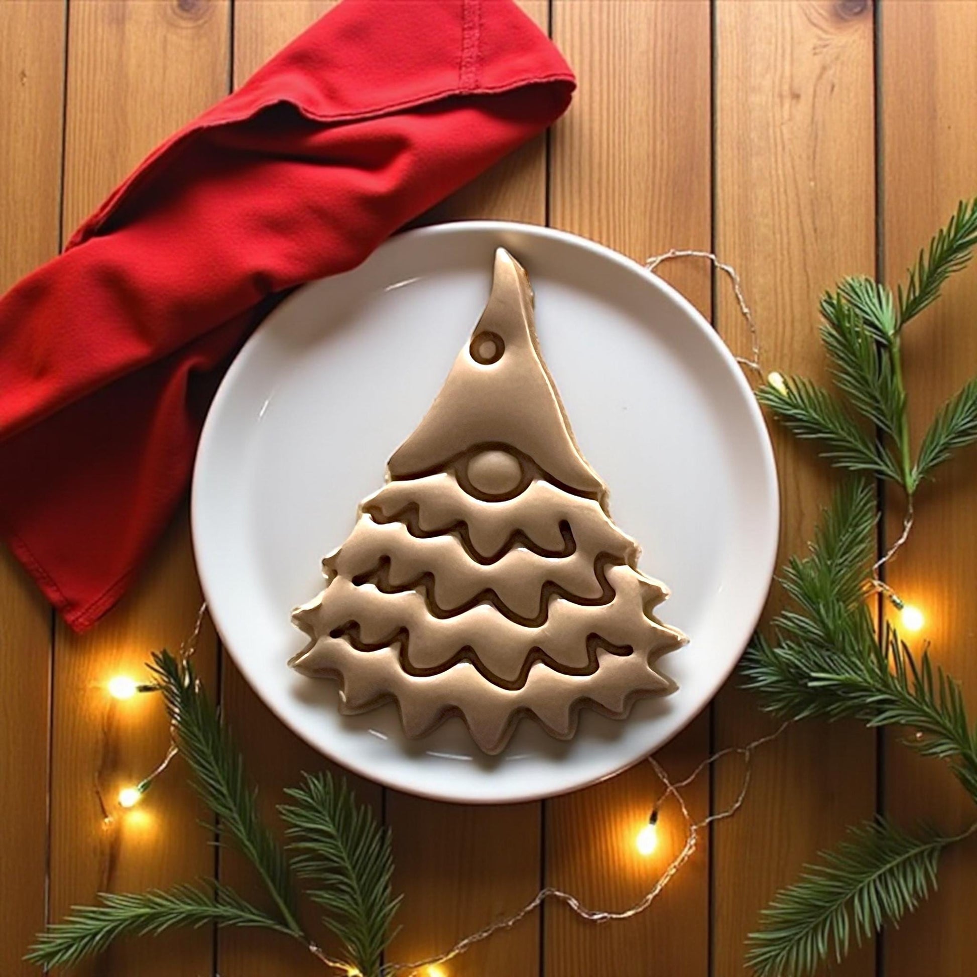 Large gnome tree clay impression on white plate with red napkin and pine branches