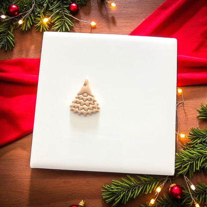 Small gnome tree clay impression on white tile surrounded by pine and lights