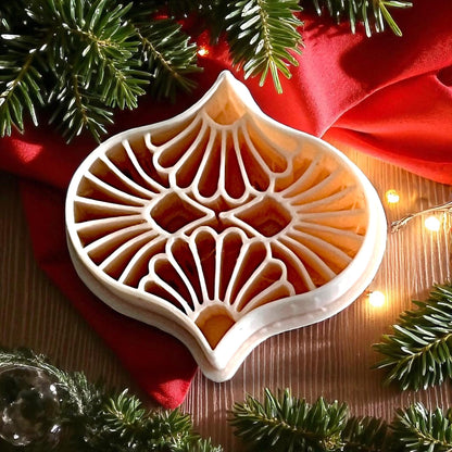 detailed ornament polymer clay cutter on red fabric with pine branches and lights