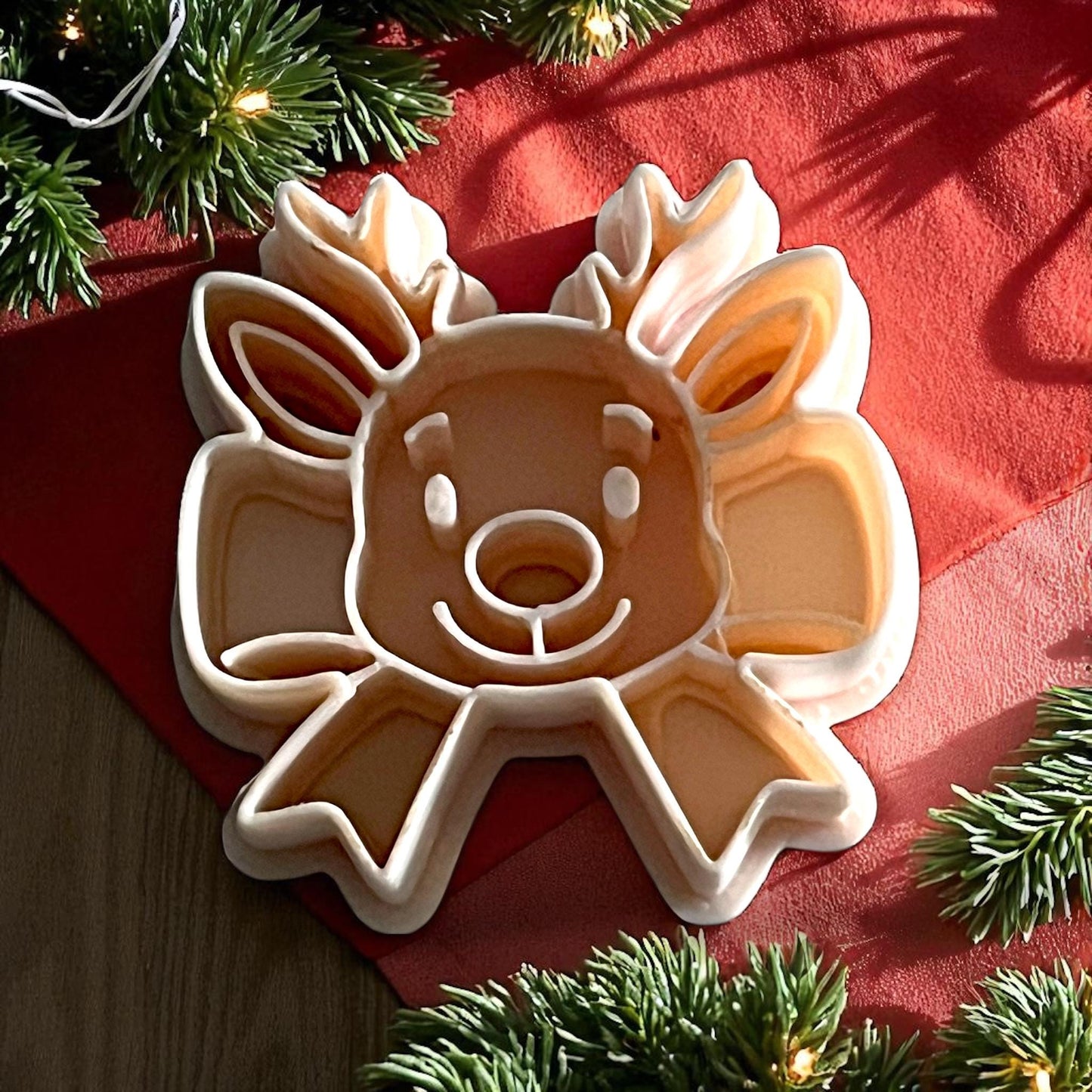 reindeer ribbon bow polymer clay cutter on red cloth with pine branches and lights