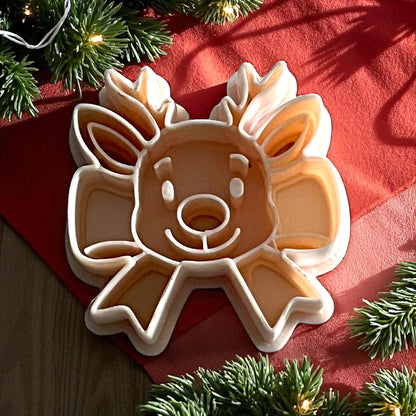 reindeer ribbon bow polymer clay cutter on red cloth with pine branches and lights