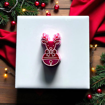Pink reindeer clay imprint with antlers and bow on white tile