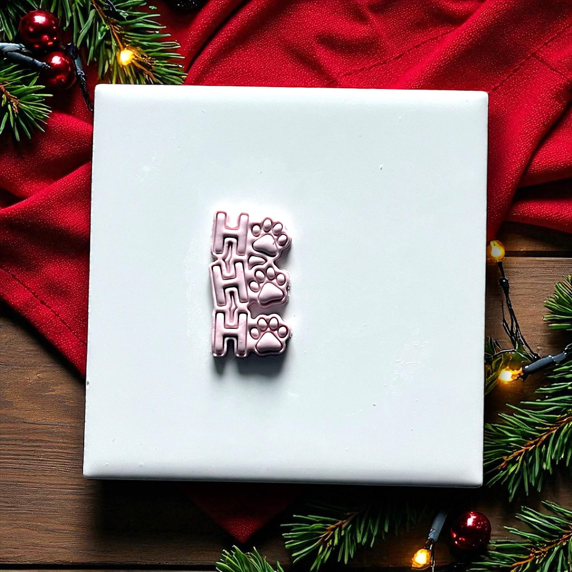 Ho Ho Ho paw print polymer clay imprint on white tile with holiday background