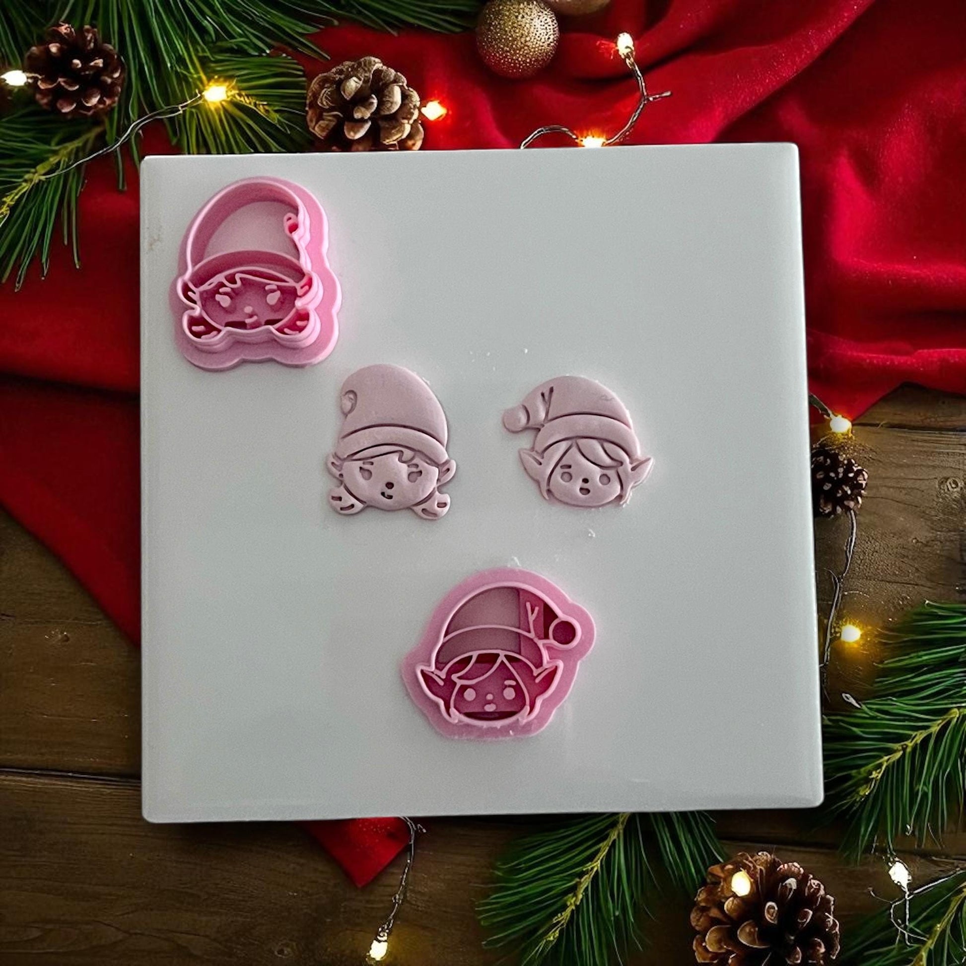 Elf boy and girl polymer clay cutters with clay imprints on white tile and holiday decor