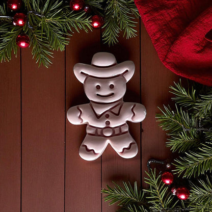 Cowboy gingerbread man imprint on pink clay slab with holiday background