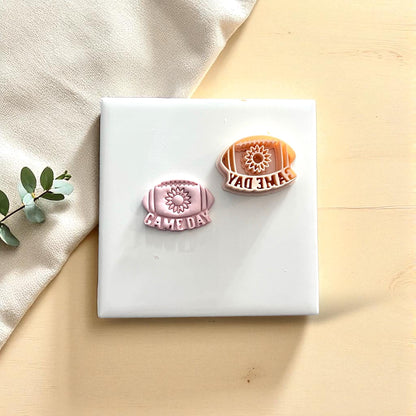 Two sunflower football game day clay imprints with cutters on white tile