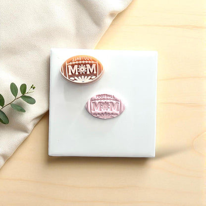 Two football mom clay imprints in pink and orange with cutters