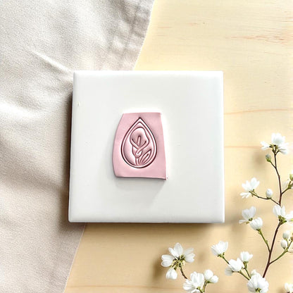 Calla lily polymer clay imprint in teardrop shape on white tile