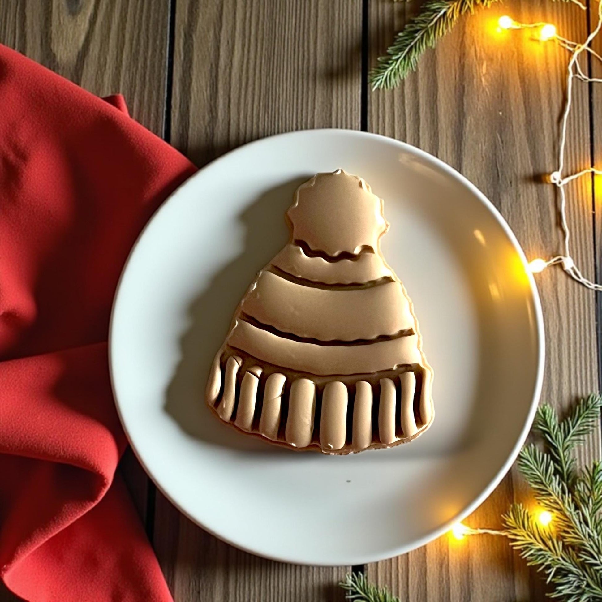 Close-up of large beanie clay design on plate with lights and pine branches