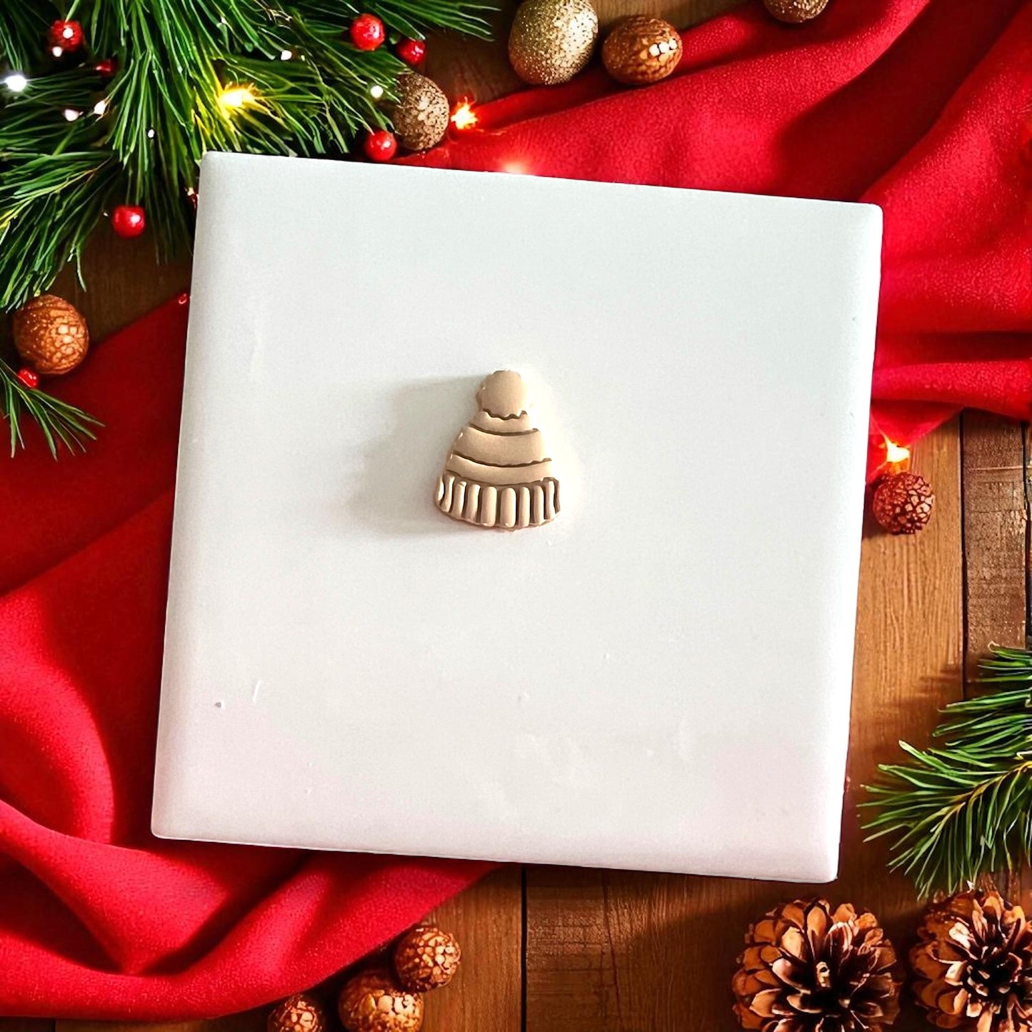 Beanie clay cutter and impression shown side by side on white tile