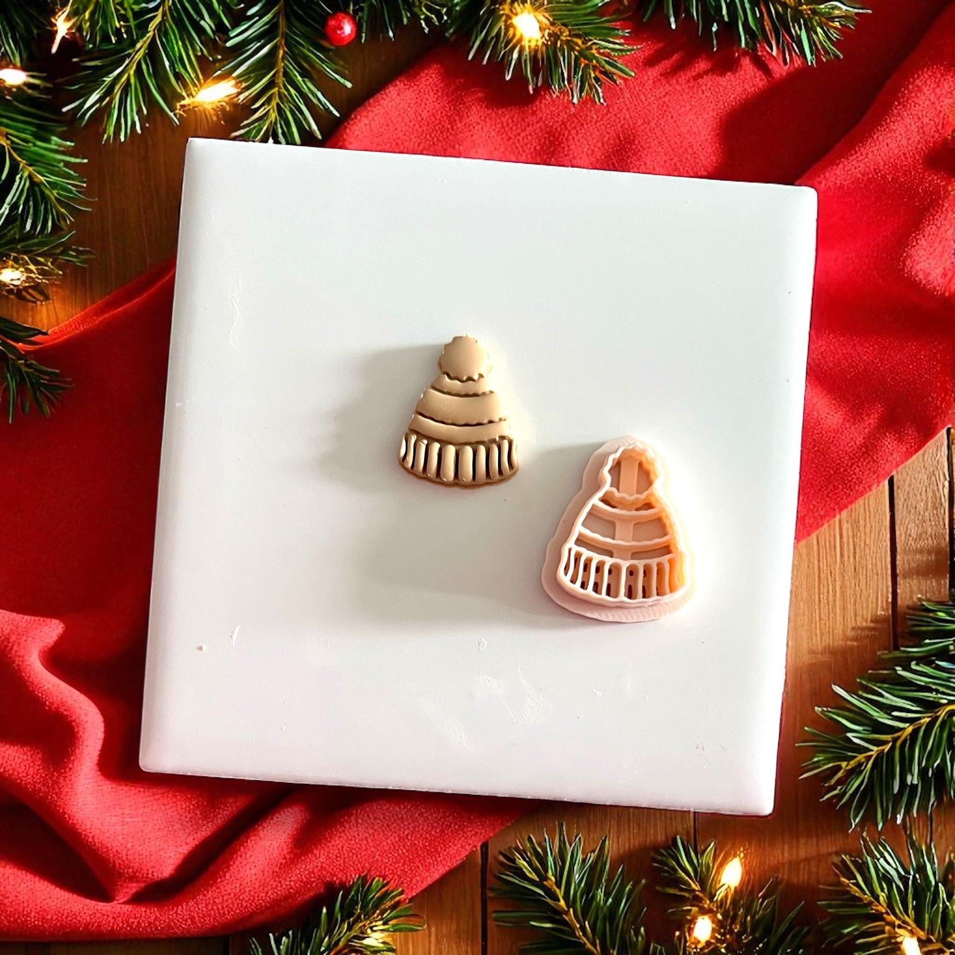 Beanie clay piece displayed on white tile with red holiday backdrop