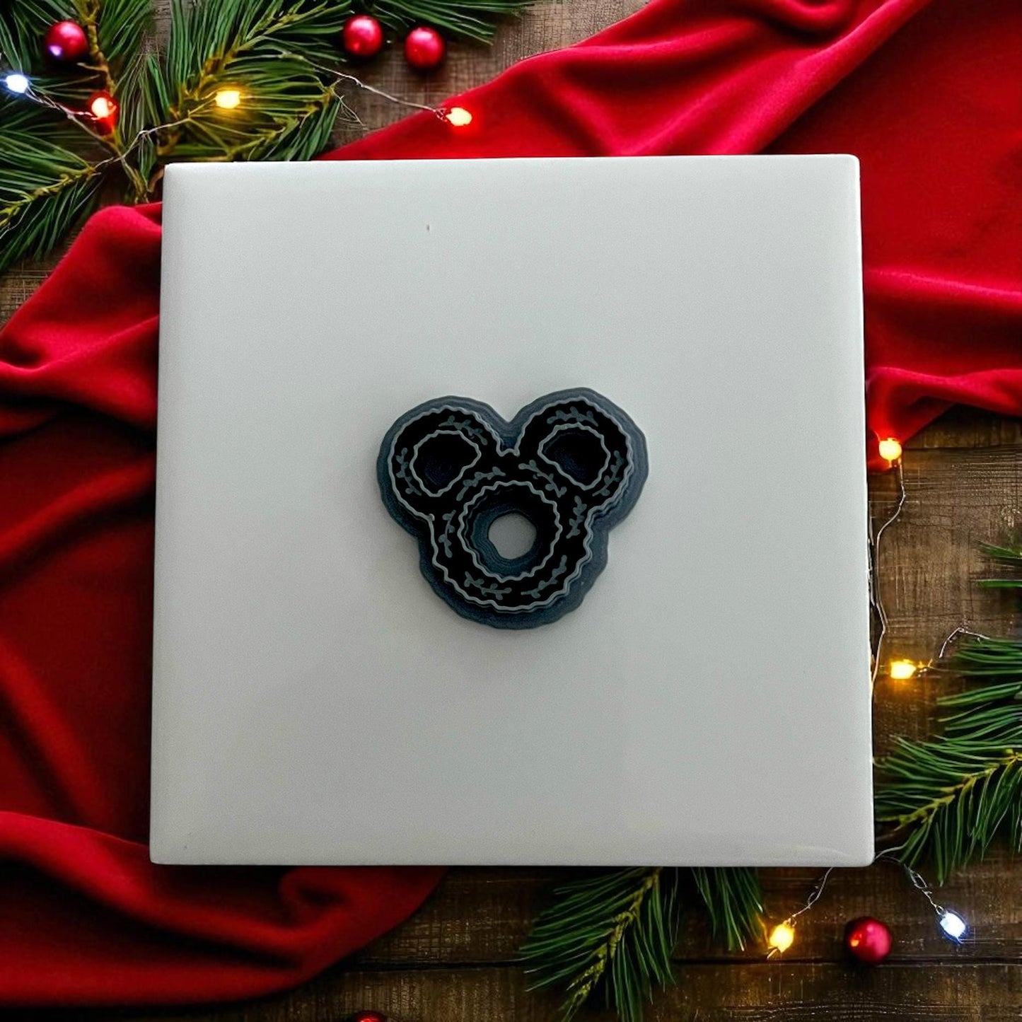 polymer clay wreath next to black cutter on white tile