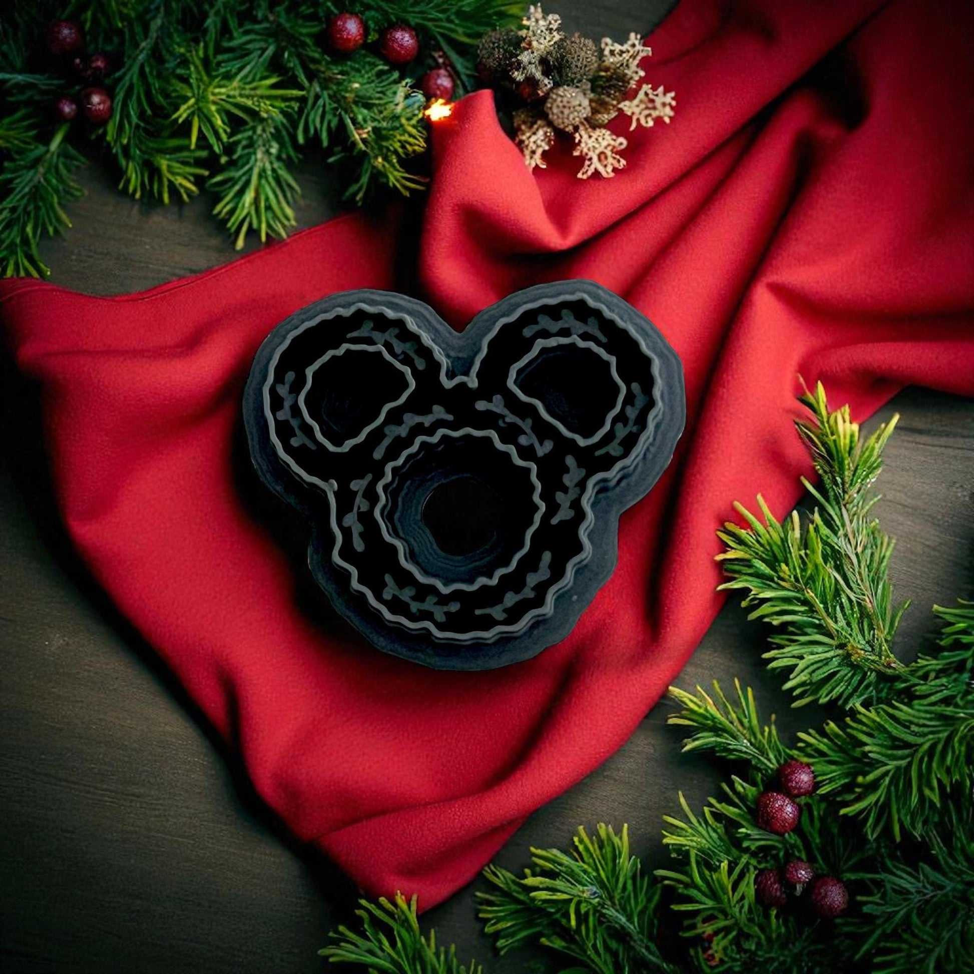 black wreath-shaped clay cutter on white tile with red background