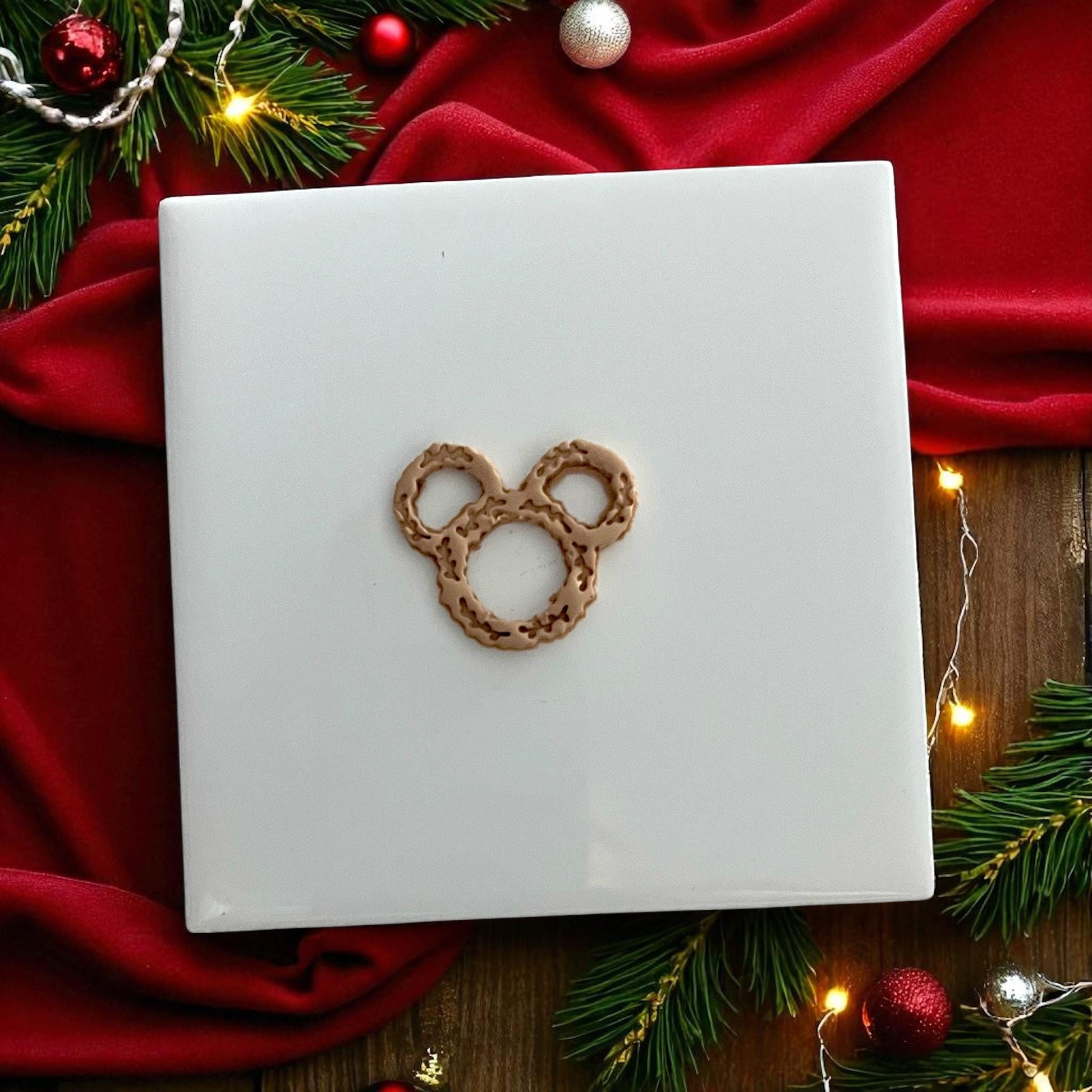 clay impression of wreath-shaped cutter with festive red backdrop