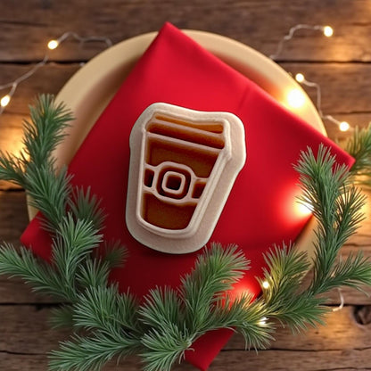 Santa coffee cup cutter on red napkin with pine greenery and Christmas lights