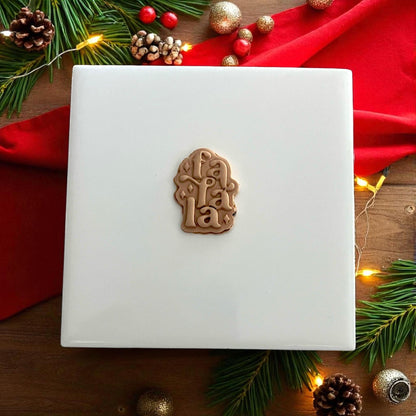 Fa La La clay impression on white tile with gold and red Christmas decor