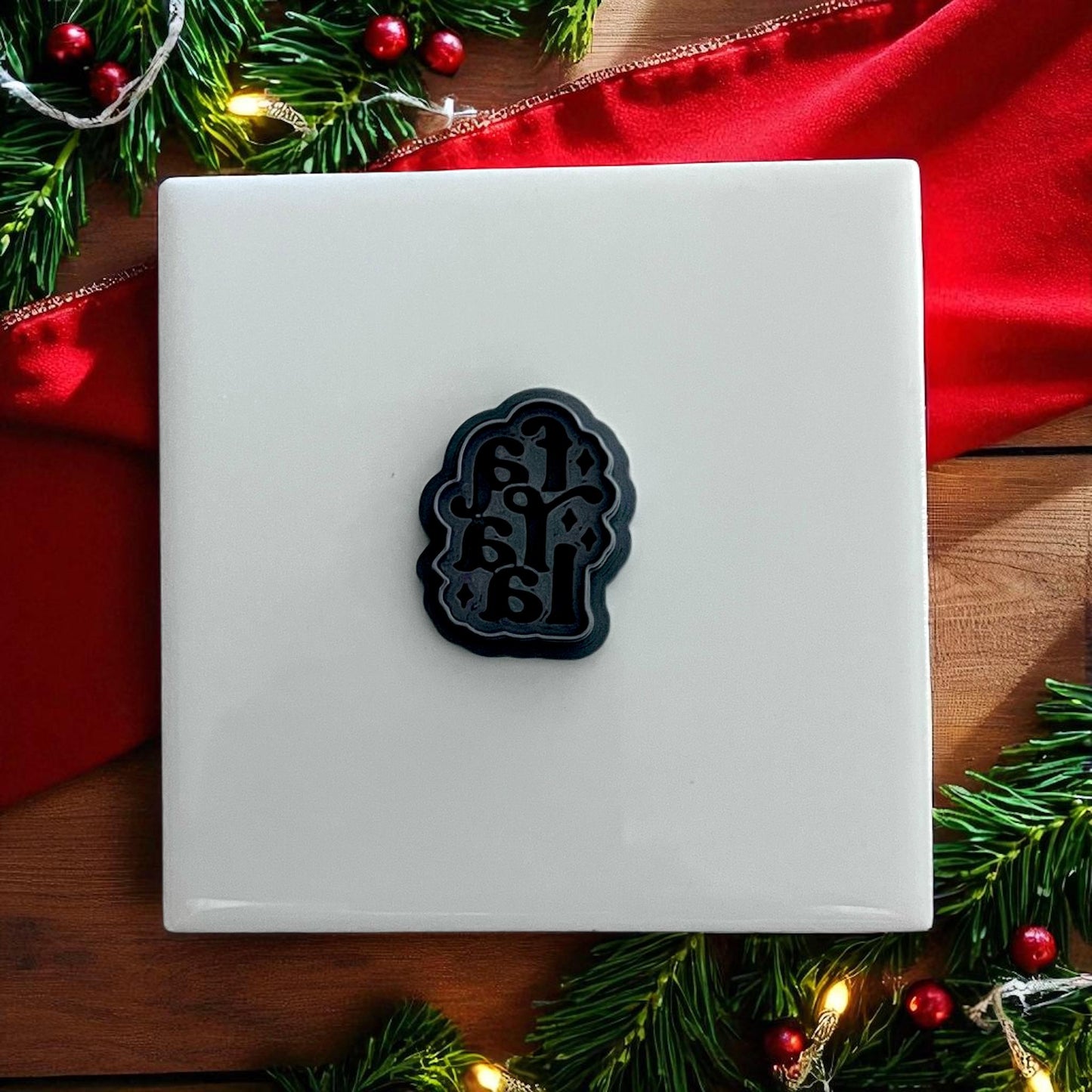 Fa La La cutter on white tile with red ribbon and greenery