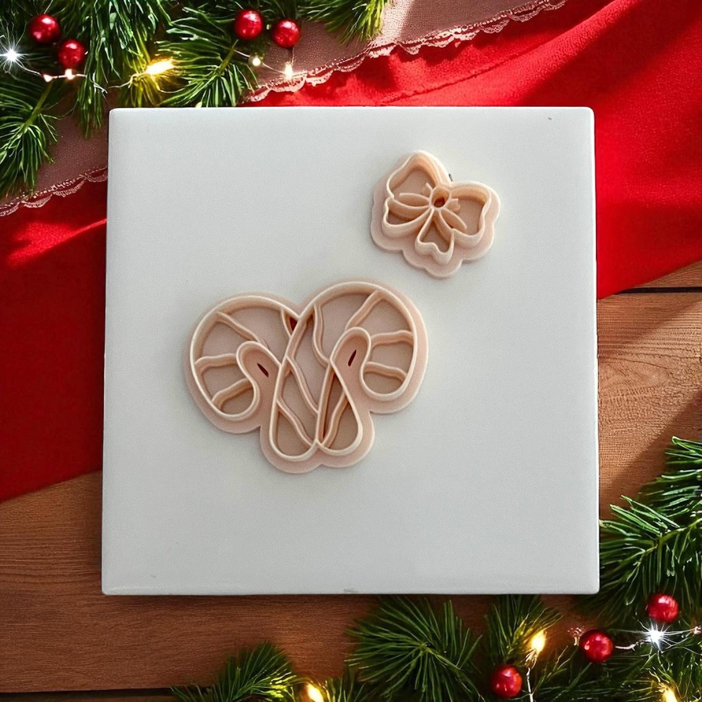 Candy cane bow polymer clay cutter set with impression on white tile and red holiday decor