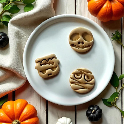 Skull, mummy, and Frankenstein clay imprints on white plate surrounded by pumpkins