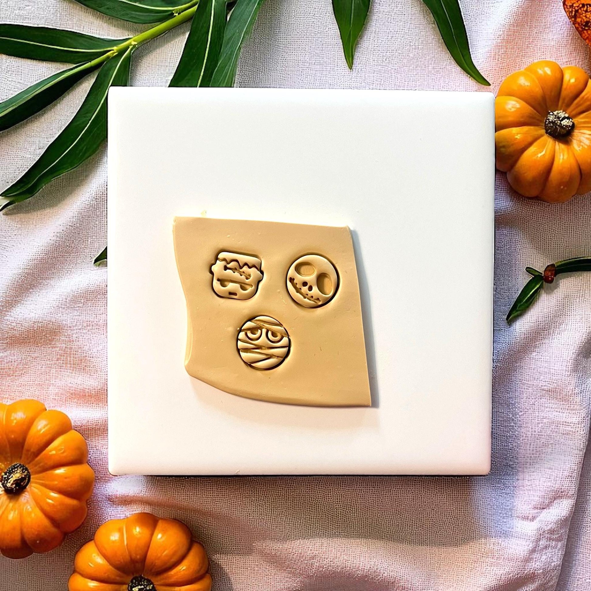 Halloween polymer clay imprints of skull, mummy, and Frankenstein on flat clay sheet