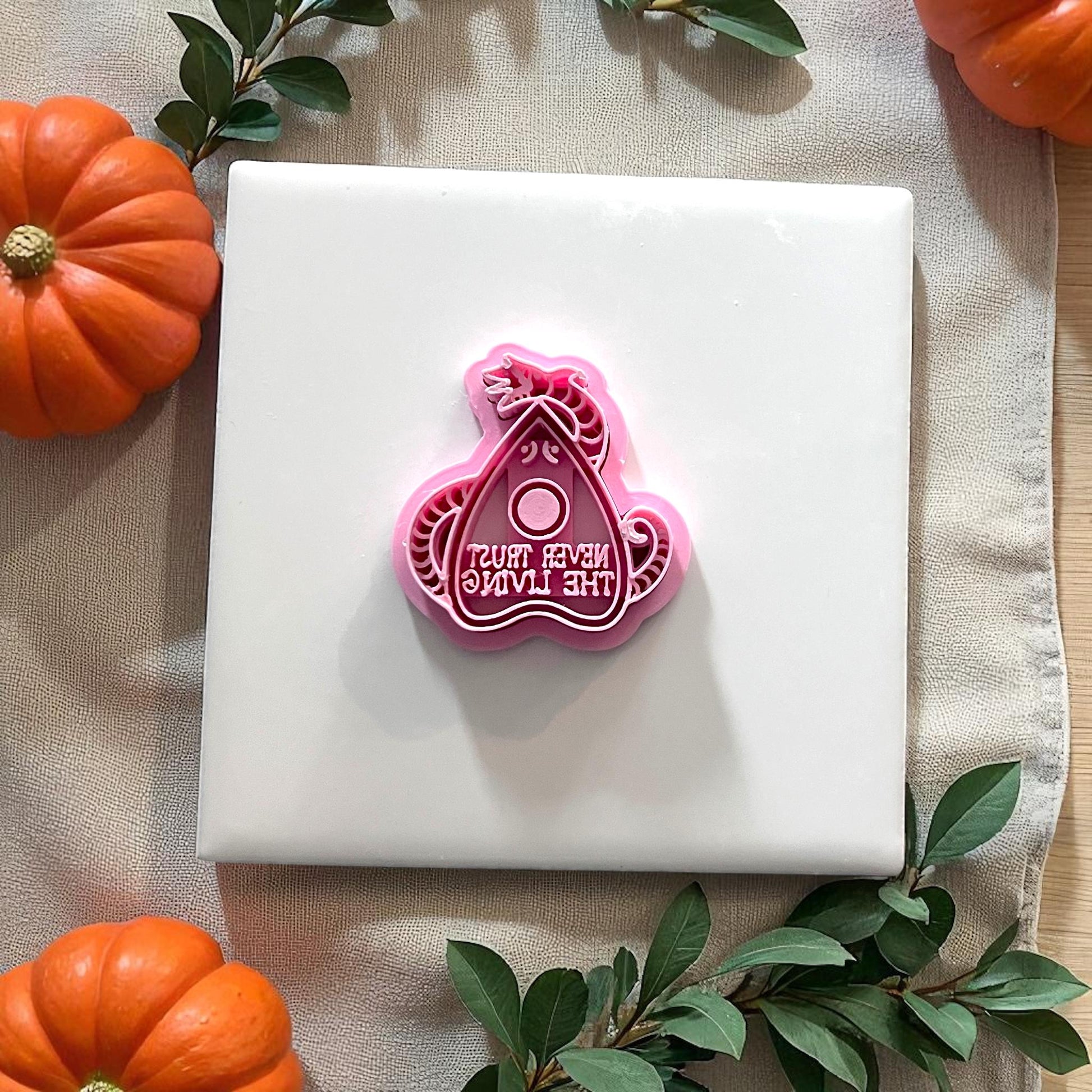 Pink Halloween planchette polymer clay cutter with Never Trust the Living text