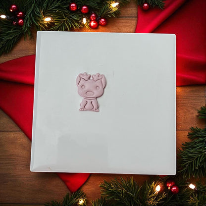 Dog with reindeer ears clay imprint surrounded by Christmas greenery and lights