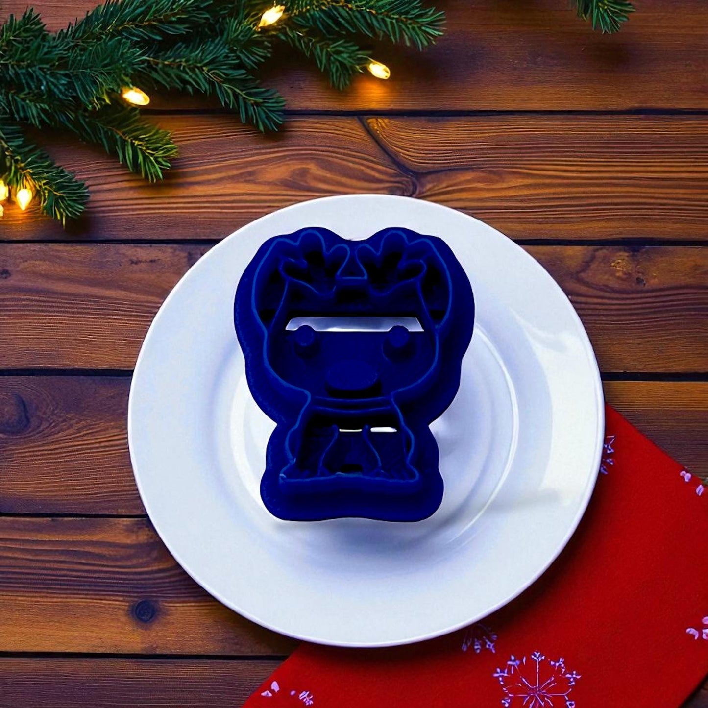 Blue dog with reindeer antlers clay cutter on white plate with holiday greenery