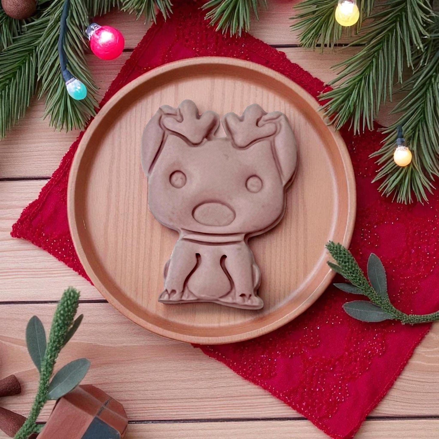 Large brown clay imprint of dog with reindeer ears on wooden plate with red napkin