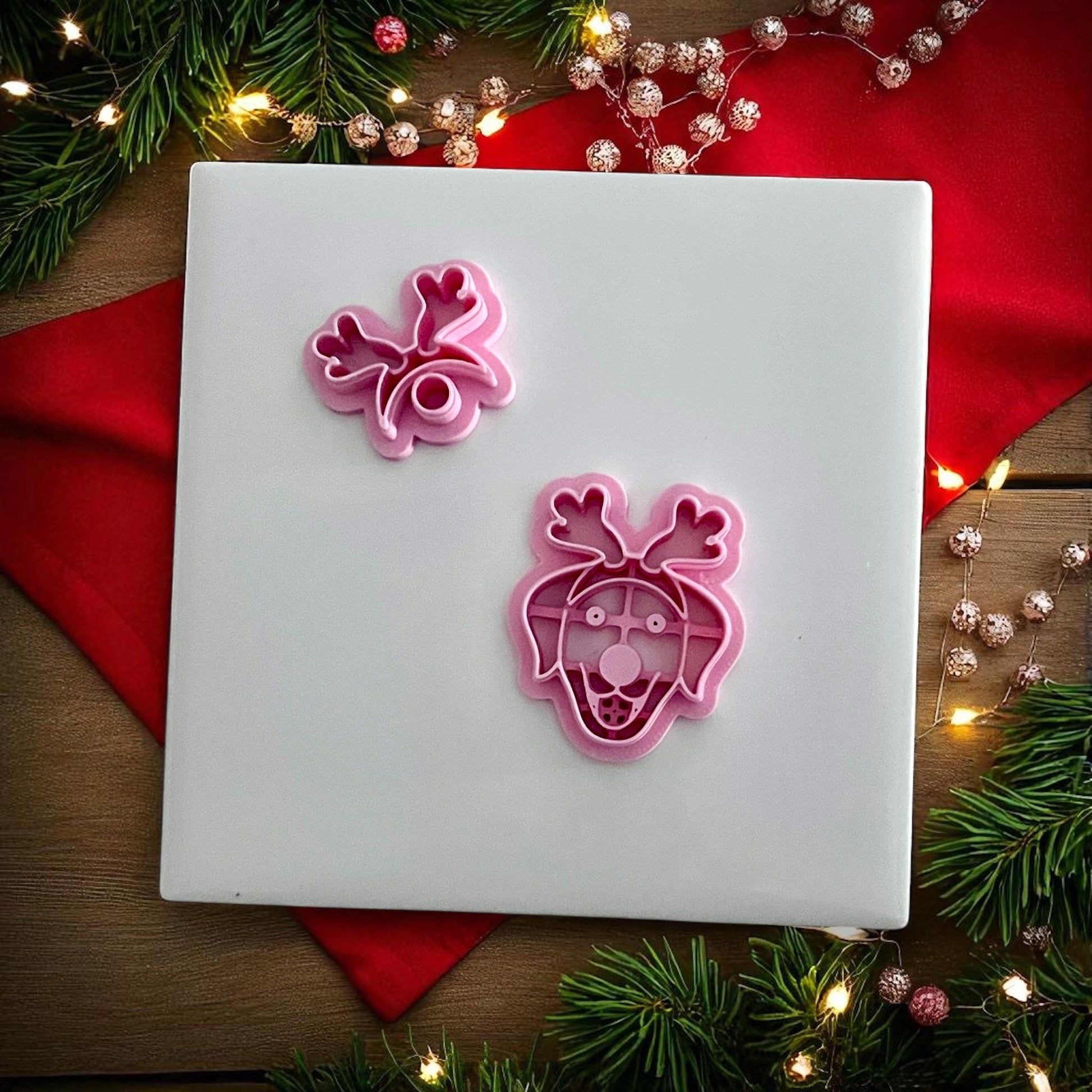 Pink polymer clay cutter set showing labrador dog face with reindeer antlers on white tile
