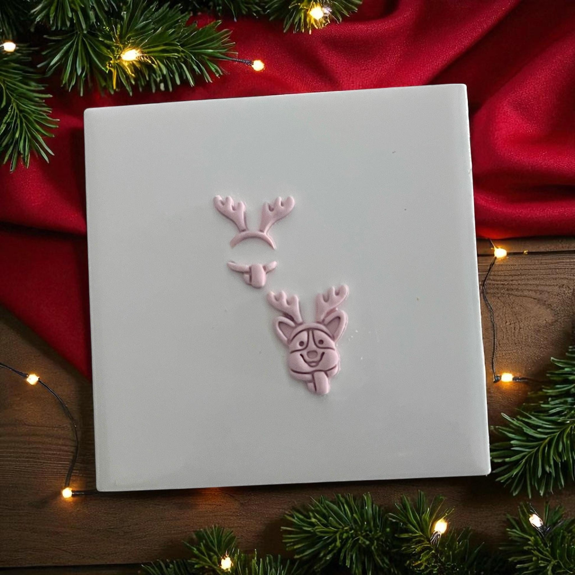 Corgi with antlers clay imprint shown in pieces on white tile surrounded by holiday lights