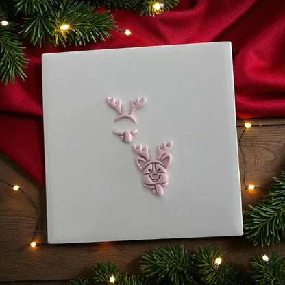 Corgi with antlers clay imprint shown in pieces on white tile surrounded by holiday lights