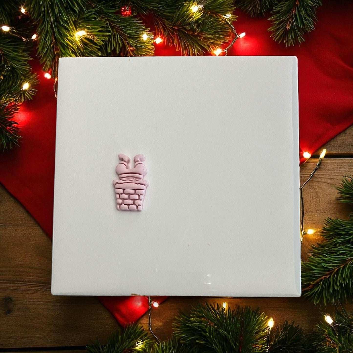 Small Santa in chimney clay imprint with Christmas lights and greenery