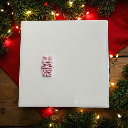 Small Santa in chimney clay imprint with Christmas lights and greenery
