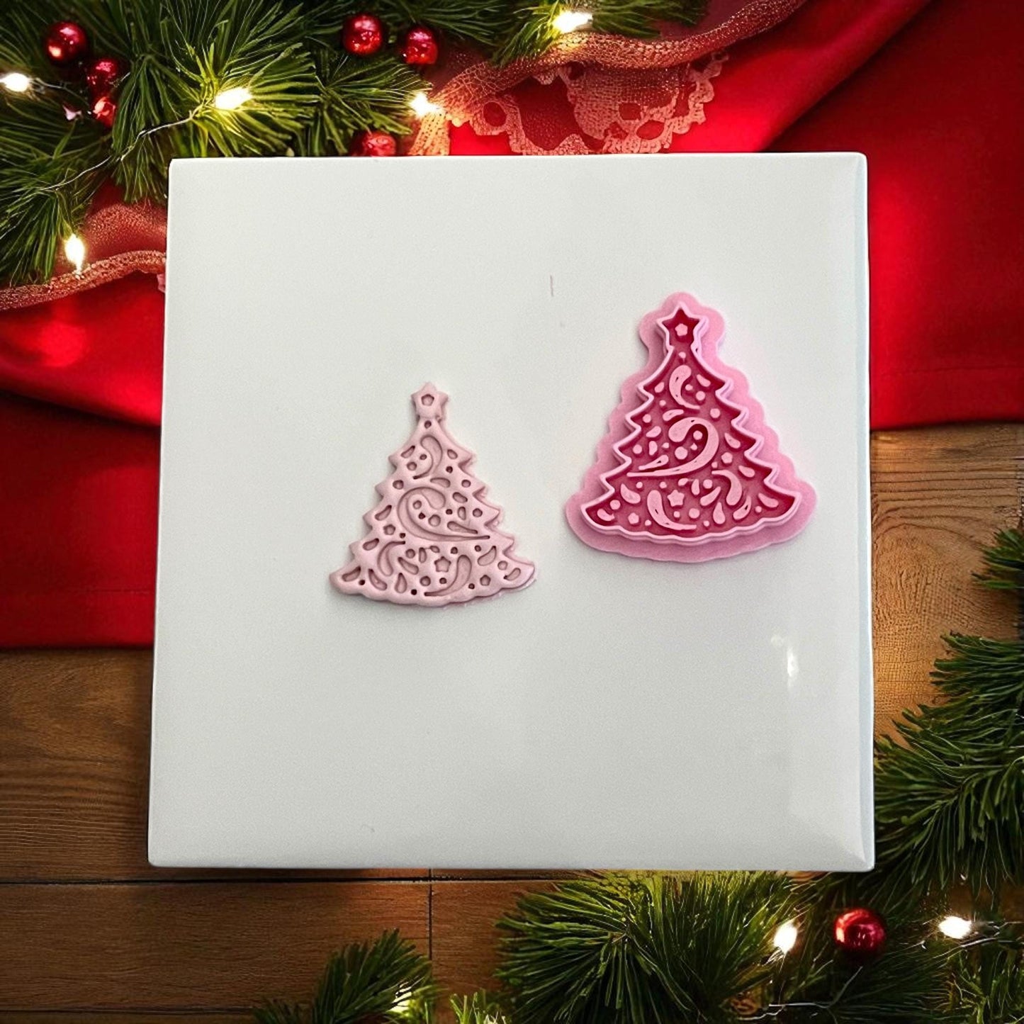 Pink swirly Christmas tree clay imprint and cutter side by side on white tile