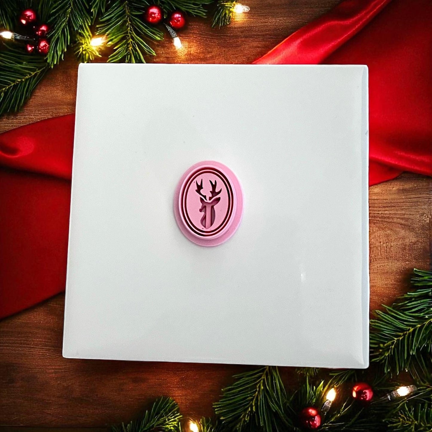 Pink reindeer cameo polymer clay cutter on white tile with festive holiday backdrop