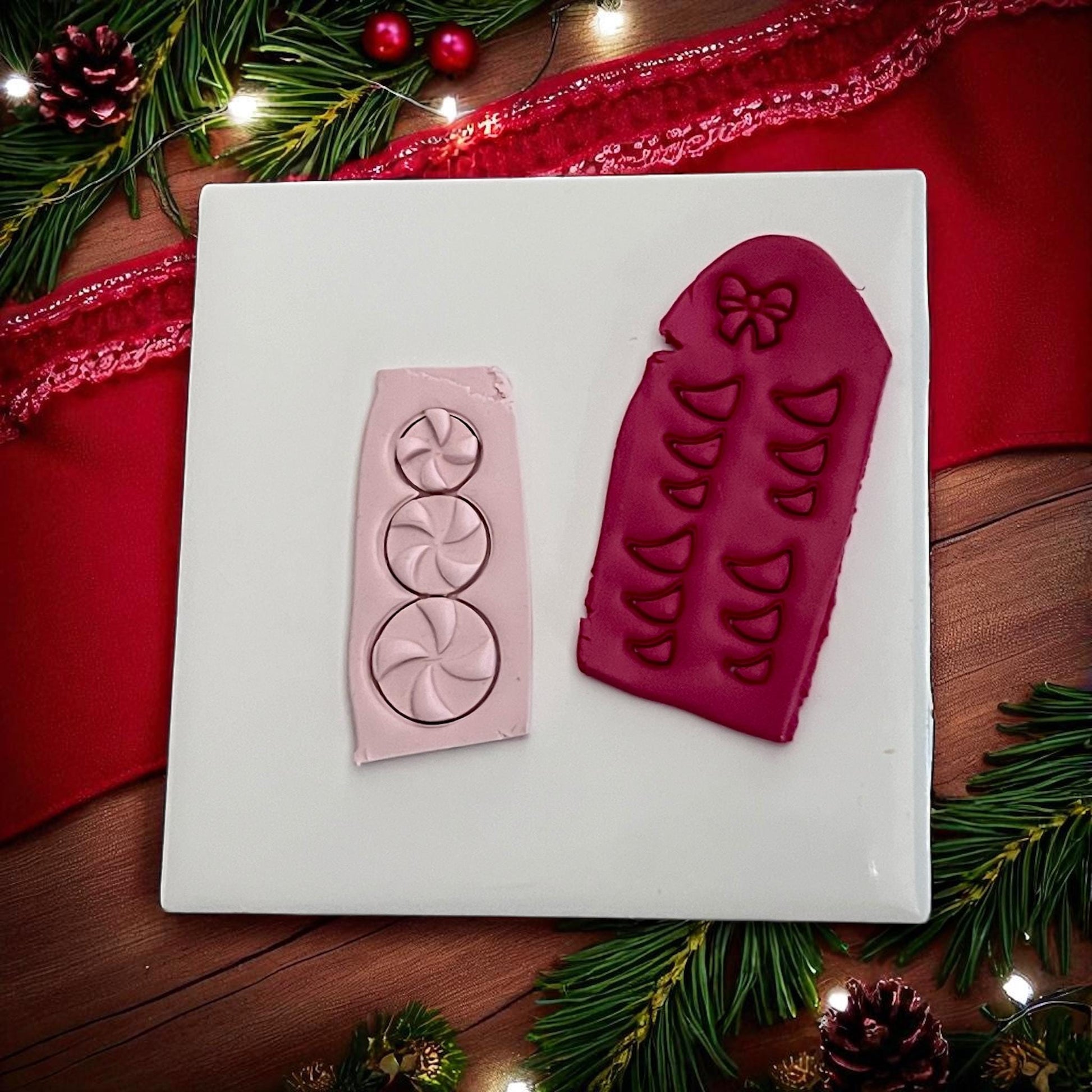 Pink and red clay imprints of peppermint candy snowman with bow cutter on white tile