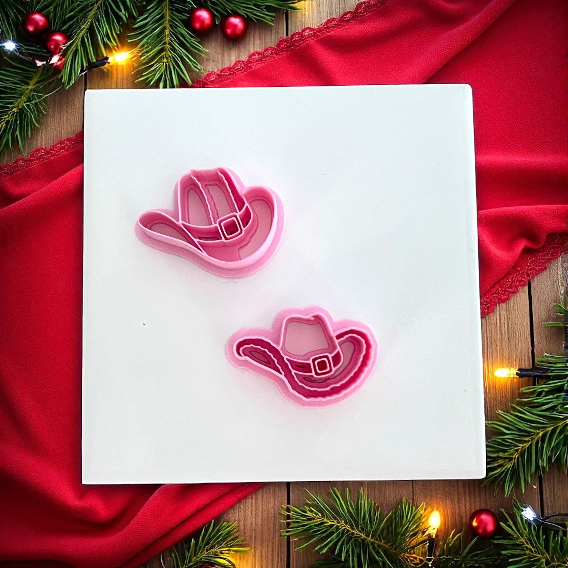 Christmas cowboy hat clay impressions in red and pink on white tile with lights