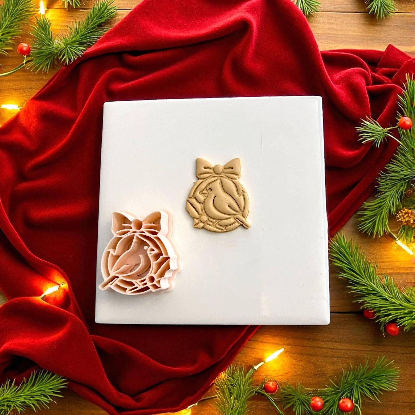 Christmas bird polymer clay cutter beside clay imprint on red velvet background