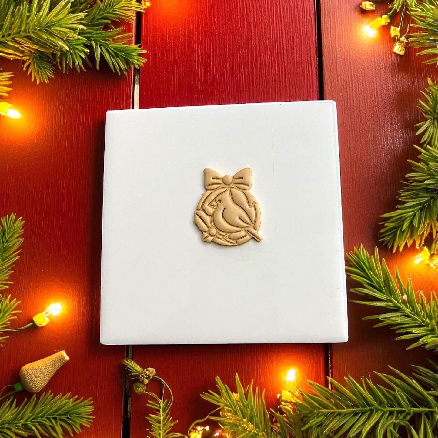 Holiday cardinal clay imprint on white tile with red background and string lights