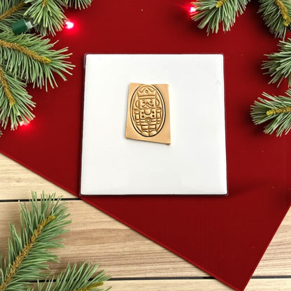 Nutcracker polymer clay imprint on tan clay with red background and Christmas lights