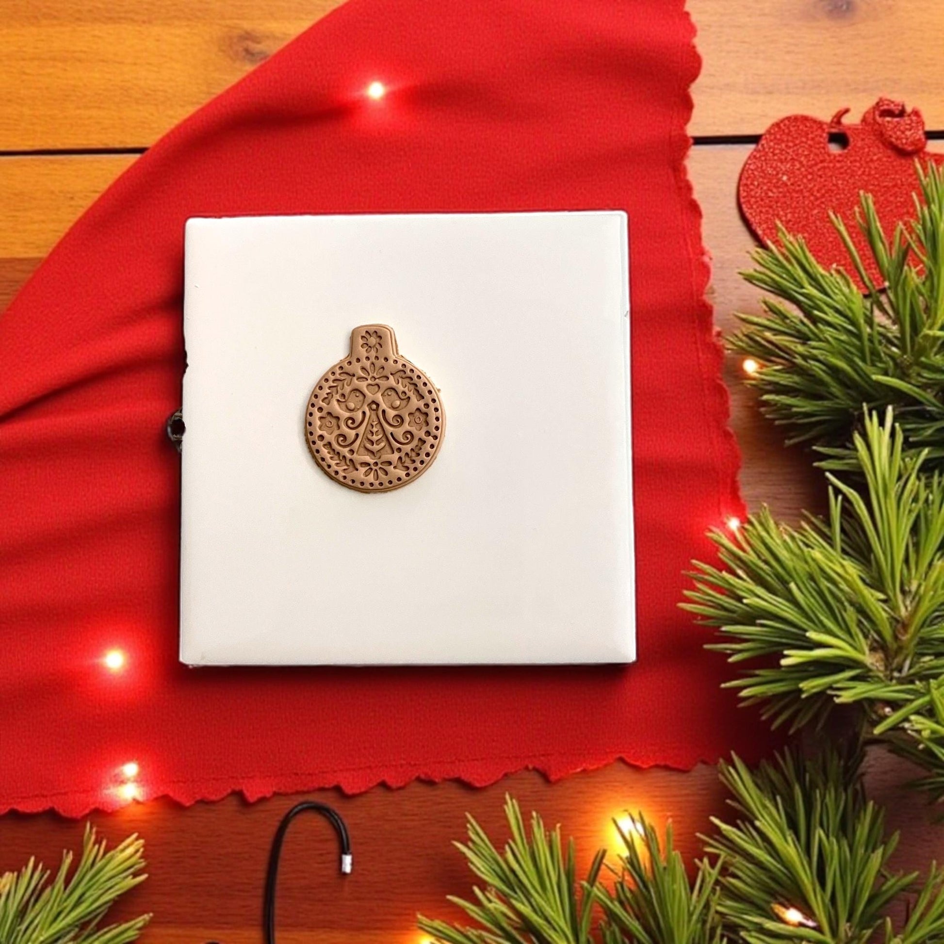 Nordic folk ornament clay design on white tile with red background and pine sprigs